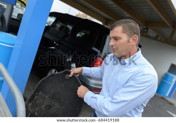 man cleaning a car\
mat