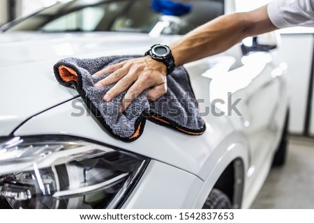 A man cleaning car with microfiber cloth, car detailing (or valeting) concept. Selective focus.