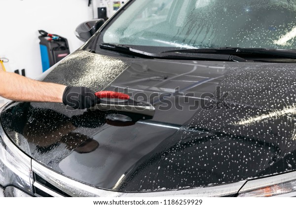 A man cleaning car with microfiber cloth, car\
detailing (or valeting) concept. Selective focus. Car detailing.\
Cleaning with sponge. Worker cleaning. Microfiber and cleaning\
solution to clean