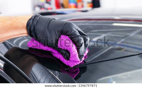 A man\
cleaning car with microfiber cloth. Car detailing or valeting\
concept. Selective focus. Car detailing. Cleaning with sponge.\
Worker cleaning. Car wash concept solution to\
clean