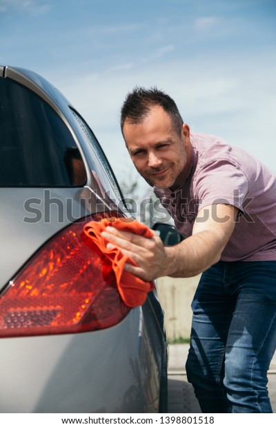 Man cleaning car with\
microfiber cloth