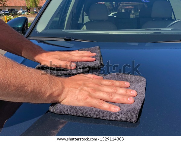 A man cleaning car with\
microfiber cloth, car detailing concept. Hand of employees worker\
use clean dark cloth to wipe the car after washing in the car wash\
shop