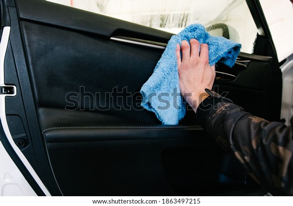 A man cleaning car with microfiber cloth, car\
detailing concept. Selective focus.Man polishing cleaning car with\
microfiber cloth