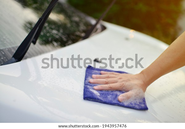 Man\
cleaning car with microfiber cloth at car\
wash