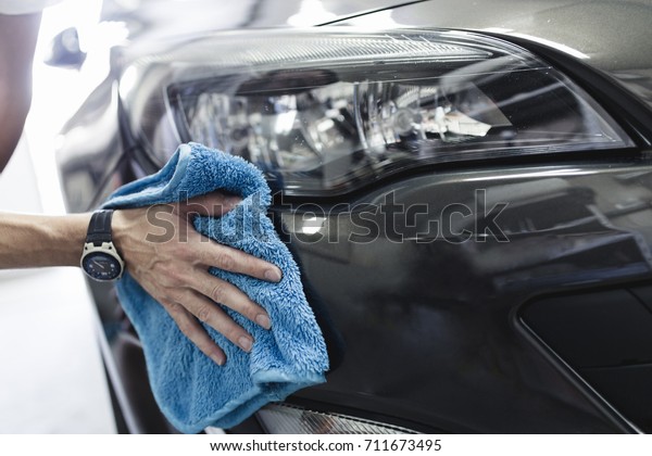A man cleaning car with
microfiber cloth, car detailing (or valeting) concept. Selective
focus.