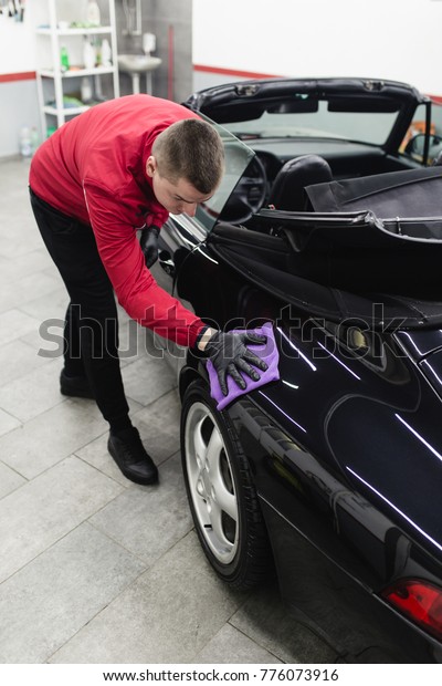 A man cleaning car with\
microfiber cloth, car detailing (or valeting) concept. Selective\
focus. 