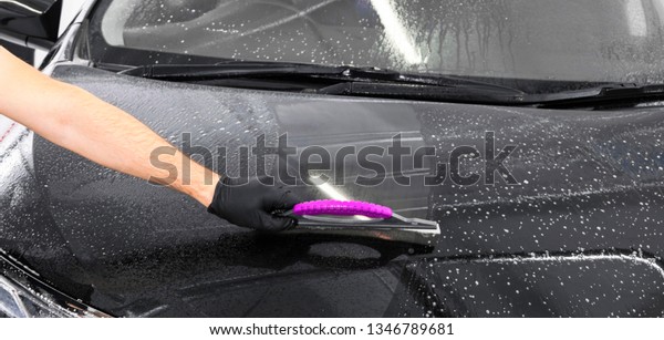 A man cleaning car with plastic sponge. Car\
detailing or valeting concept. Selective focus. Car detailing.\
Cleaning with sponge and cloth. Worker cleaning. Car wash concept\
solution to clean