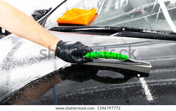 A man cleaning car with plastic sponge. Car\
detailing or valeting concept. Selective focus. Car detailing.\
Cleaning with sponge and cloth. Worker cleaning. Car wash concept\
solution to clean