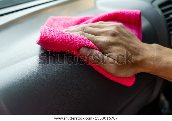 The man cleaning car seats with chemicals on\
pink microfiber cloth in the\
garden.