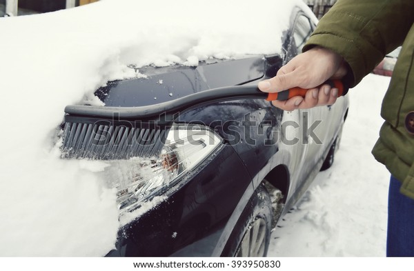 man cleaning car from snow.Transportation, winter,\
weather, people and vehicle concept - man cleaning snow from car\
with brush.