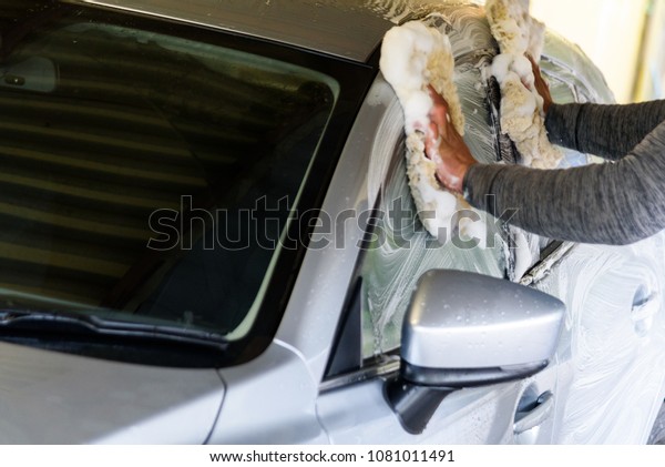 Man cleaning a car\
with soap and sponges