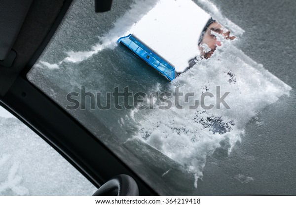 Man Cleaning\
Car Windshield From Snow and\
Ice