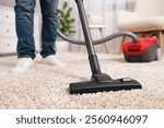 Man cleaning carpet with vacuum cleaner at home, closeup