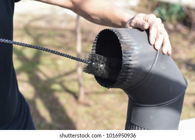 Man Cleaning Chimney Pipe Outside. Cleaning A Wood Burning Stove. Chimney Sweep Cleaning