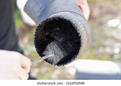 Man cleaning chimney pipe outside. Cleaning a wood burning stove. Chimney sweep cleaning
