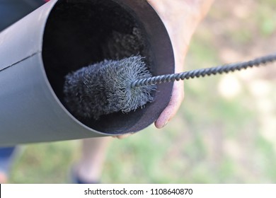 Man Cleaning Chimney Pipe Outside. Cleaning A Wood Burning Stove. Chimney Sweep Cleaning