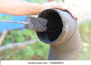 Man Cleaning Chimney Pipe Outside. Cleaning A Wood Burning Stove. Chimney Sweep Cleaning