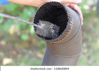 Man Cleaning Chimney Pipe Outside. Cleaning A Wood Burning Stove. Chimney Sweep Cleaning