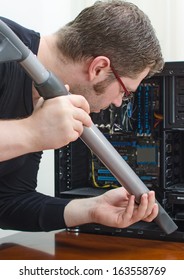 Man Cleaning Computer With Hoover