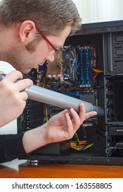 Man Cleaning Computer With Hoover