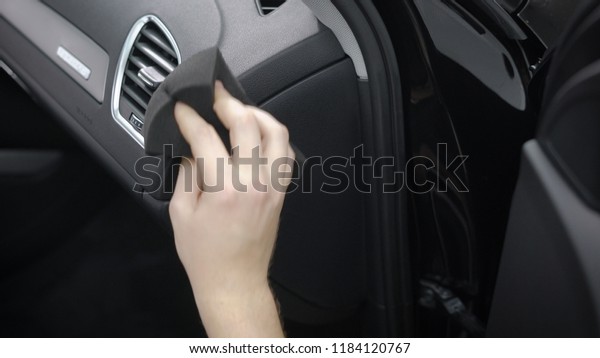 man is\
cleaning control panel inside a car, rubbing it by soft cloth,\
removing dust and dirt, close-up of male\
hand