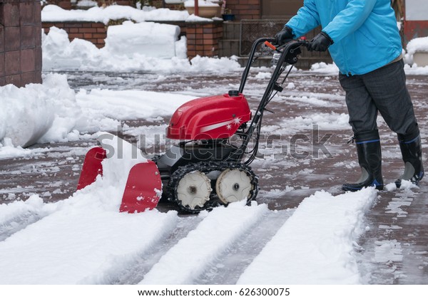 Man cleaning driveway after
a snow storm, Snow removal equipment working on the street,
Cleaning of streets from snow, It's snowing, Tractor sweeping the
street.