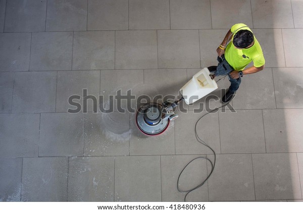 The man cleaning floor\
with machine.