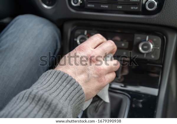 Man cleaning front dashboard of a car using\
antivirus antibacterial wet wipe (napkin) for protect himself from\
bacteria and virus.