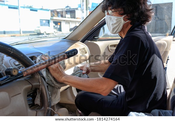Man cleaning his car\
with face mask on