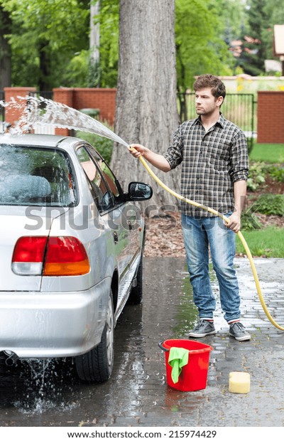 Man cleaning his car\
in front of house