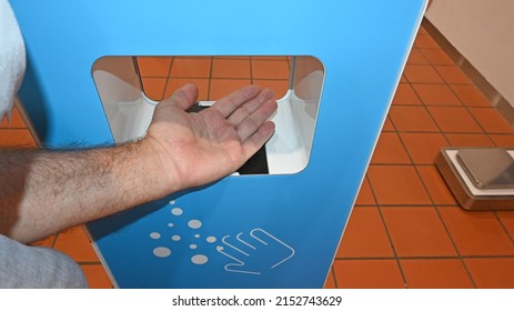 Man Cleaning His Hands In A Hand Cleaning Station At A Shopping Centre