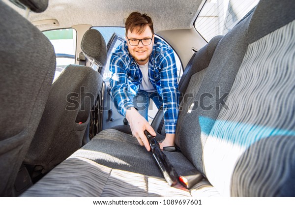 man cleaning inside car with vacuum cleaner.\
carwash concept