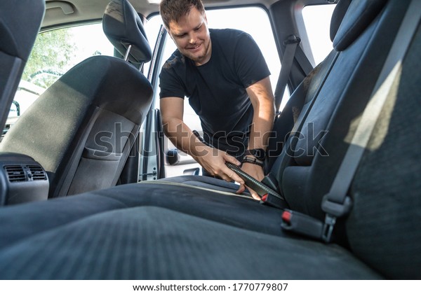 man cleaning\
inside car with vacuum\
cleaner