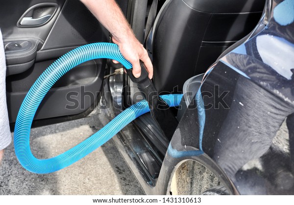 Man\
cleaning the interior of the car with vacuum\
cleaner