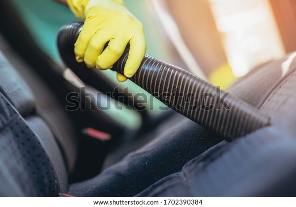 Man\
cleaning the interior of his car with vacuum\
cleaner