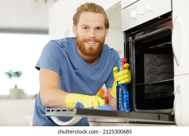 Man Cleaning Oven In Kitchen