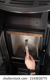 Man Cleaning Pellet Stove With Brush