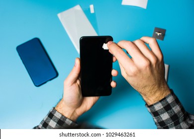 Man cleaning phone screen to apply protective tempered glass - Powered by Shutterstock