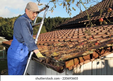 A Man Cleaning A Rain Gutter On A Ladder