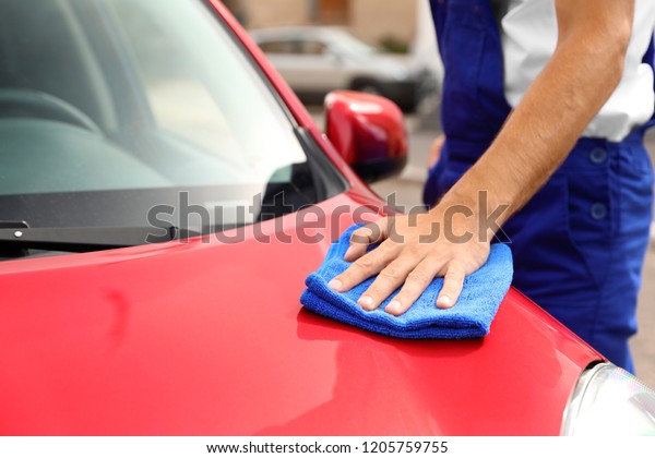 Man cleaning red auto with duster, closeup. Car
wash service