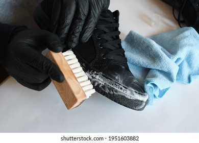 Man Is Cleaning Sneakers In A Workshop. Shoe Shine Service. The Shoemaker Prepares The Shoes For The Season. Shoe Brush Close-up. Shoe Care With A Special Product