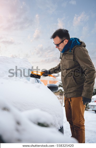 Man cleaning a snow covered car with Plastic Ice Snow\
Scraper 