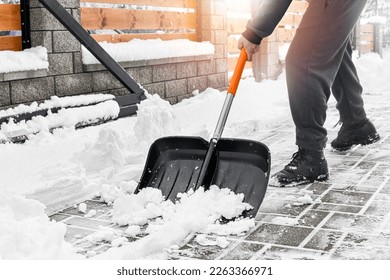 Man cleaning snow from street in winter with shovel after snowstorm. 