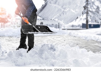 Man cleaning snow from street in winter with shovel after snowstorm. 