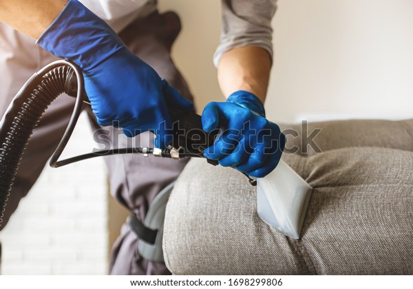Man cleaning sofa chemical cleaning with\
professionally extraction method. Upholstered furniture. Early\
spring cleaning or regular clean\
up.