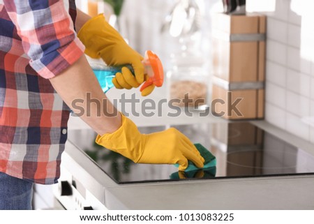 Man cleaning stove in kitchen, closeup