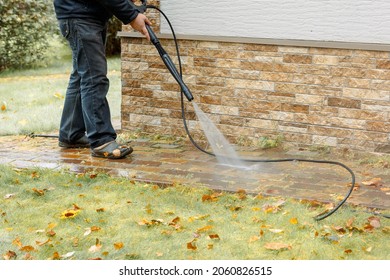 Man Cleaning Street With High Pressure Power Washer, Washing Stone Garden Paths. High Quality Photo