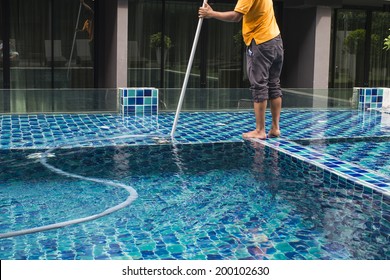 Man cleaning the swimming pool with vacuum cleaner