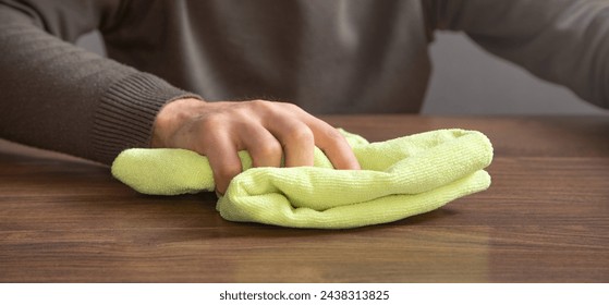 Man cleaning table using rag at home.