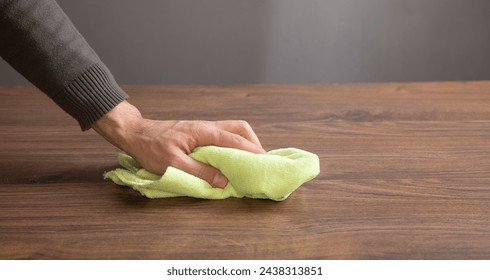 Man cleaning table using rag at home.
